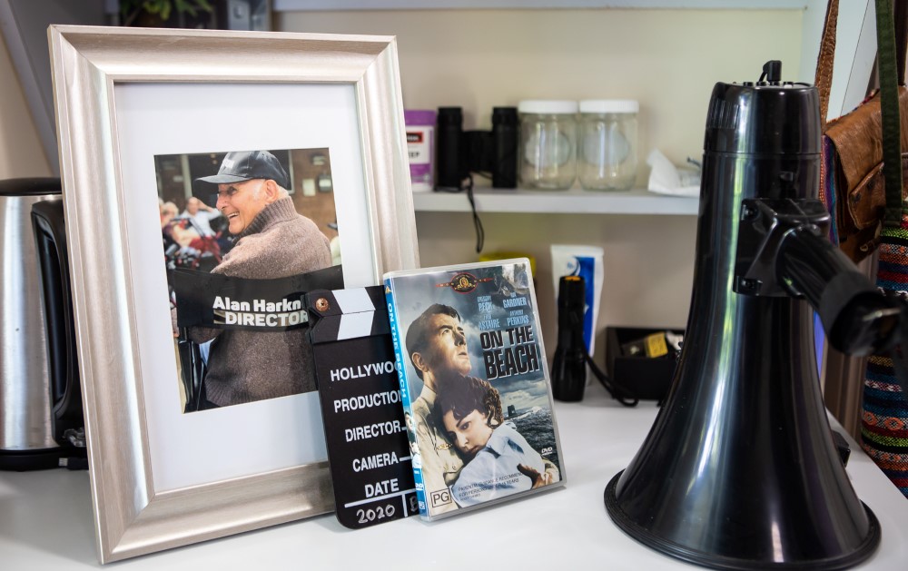 A table with a framed picture, a clapboard, a DVD of On The Beach, and a megaphone on it