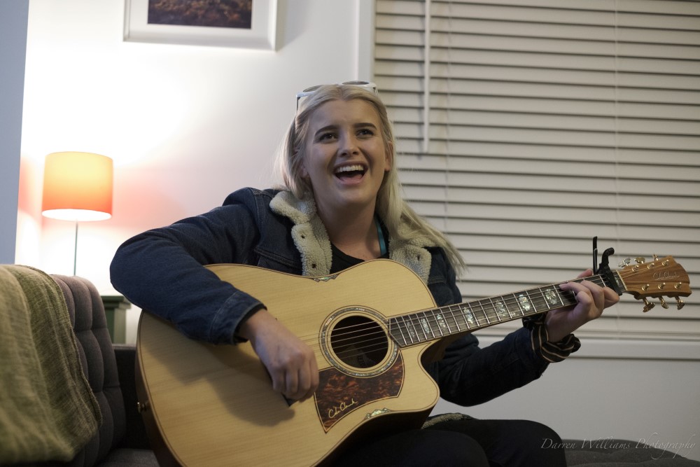 Young blonde woman playing the guitar and singing