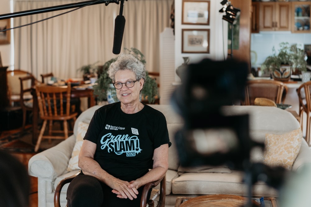 Senior lady in front of the camera, speaking in black Gran Slam T-shirt
