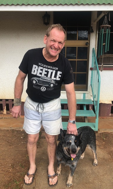 Man in his fifties wearing a Volkswagen Beetle T-shirt, holding a grey dog by the collar