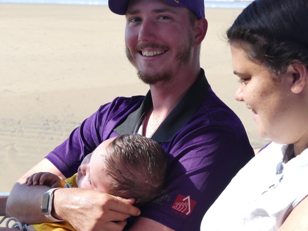 Man holding baby and smiling at camera