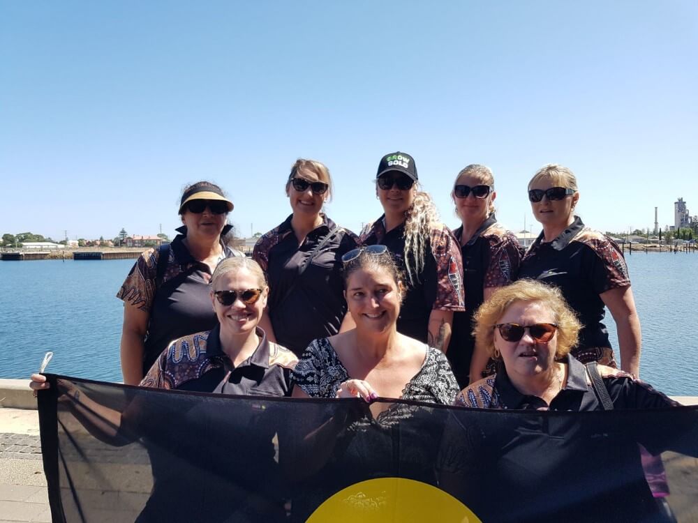 Group of women holding Aboriginal flag