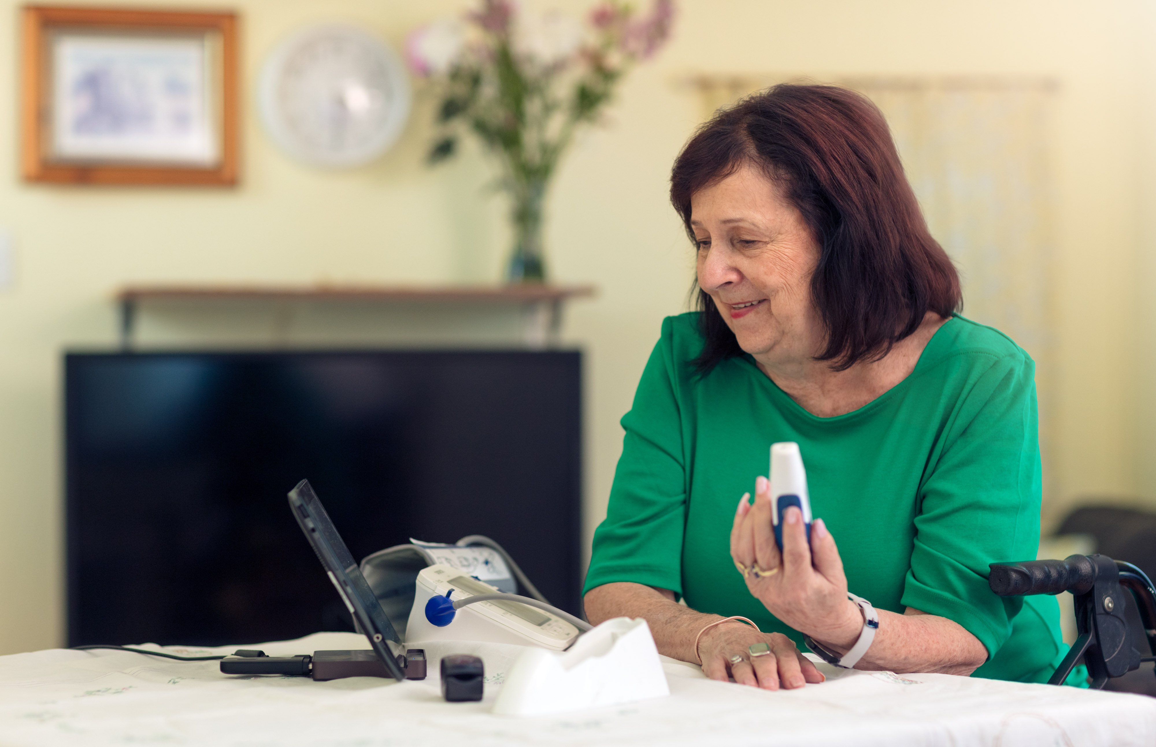 Senior lady using pulse oximeter at a table