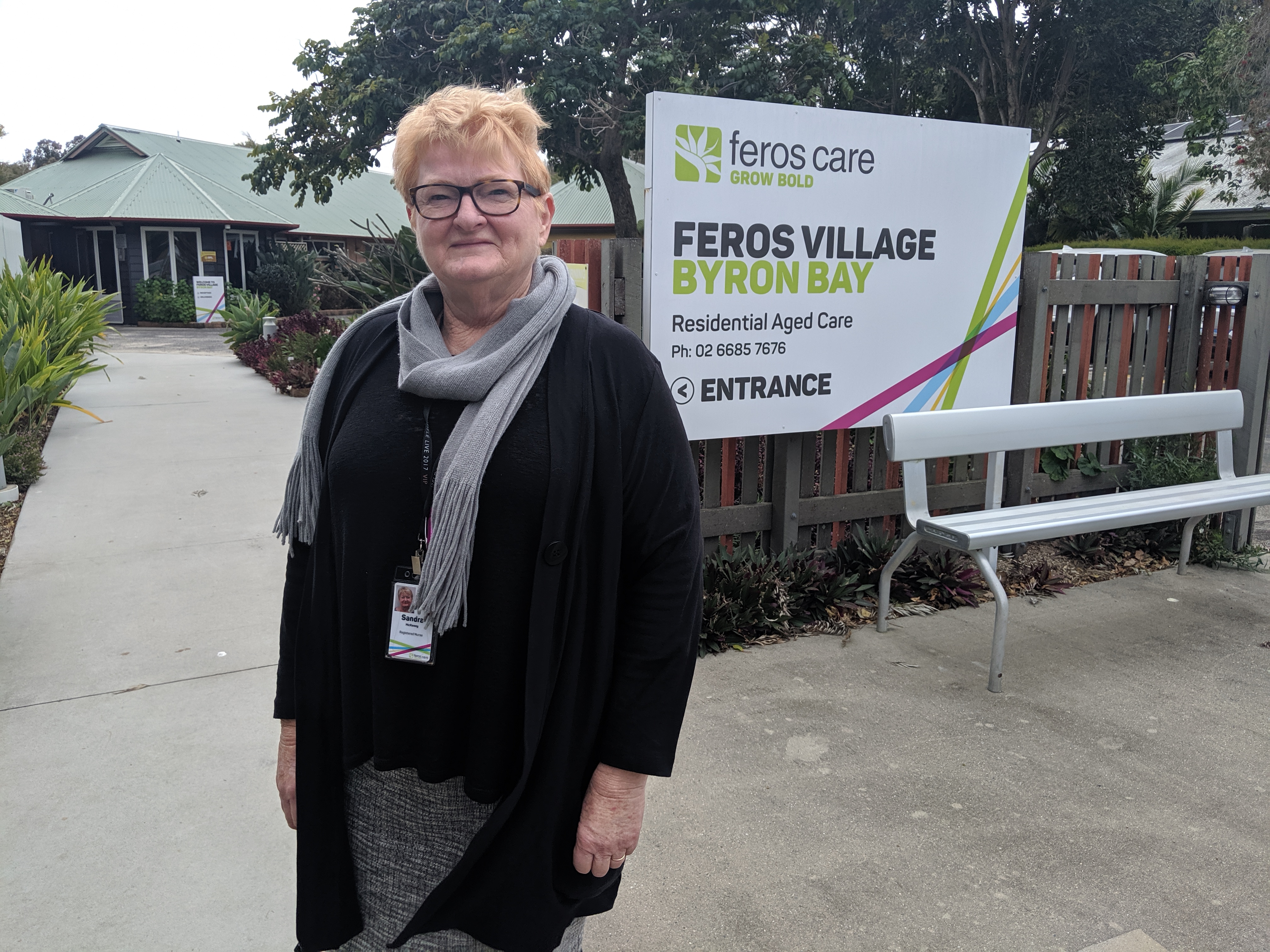 Woman standing outside Feros care Byron Bay residential Village sign