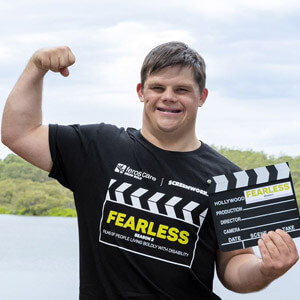 Photo of Sam Stubbs wearing Fearless Season 2 t-shirt and holding clapperboard