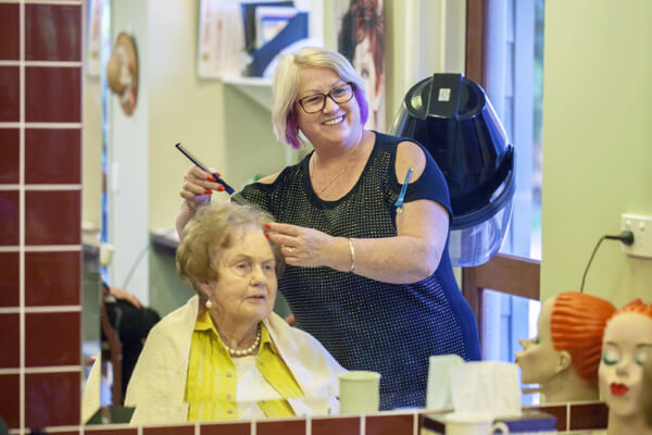 Hairdresser giving senior a hair cut