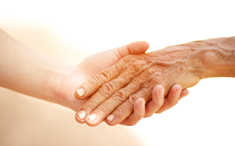 Close up of a younger person's hand holding an older person's hand
