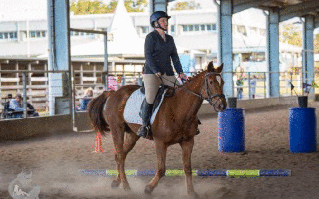 Blind equestrian competing in dressage in arena on brown horse