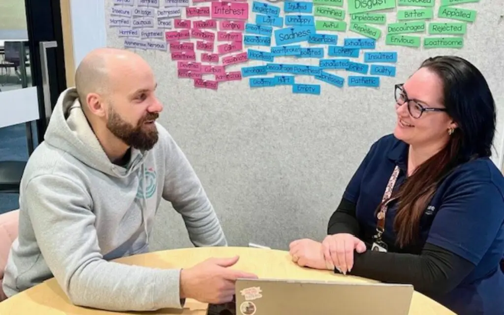 Feros Care LAC Tamika and Chris Gein, Wellbeing Lead at Compass sitting at table collaborating