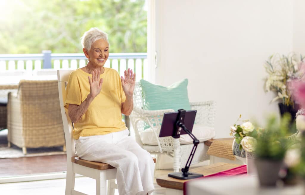 Senior holding hands up and smiling while interacting on the Virtual Social Centre
