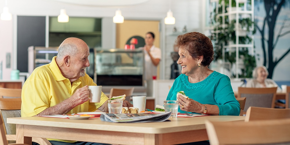 Two residents seated at a table eating lunch