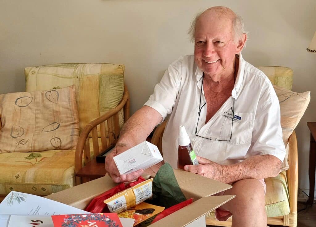 Lonely old man opening Christmas gift, hamper from charity organisation.