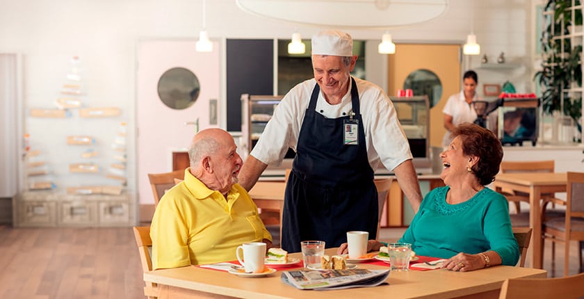 Male and female having lunch in residency cafe with chef