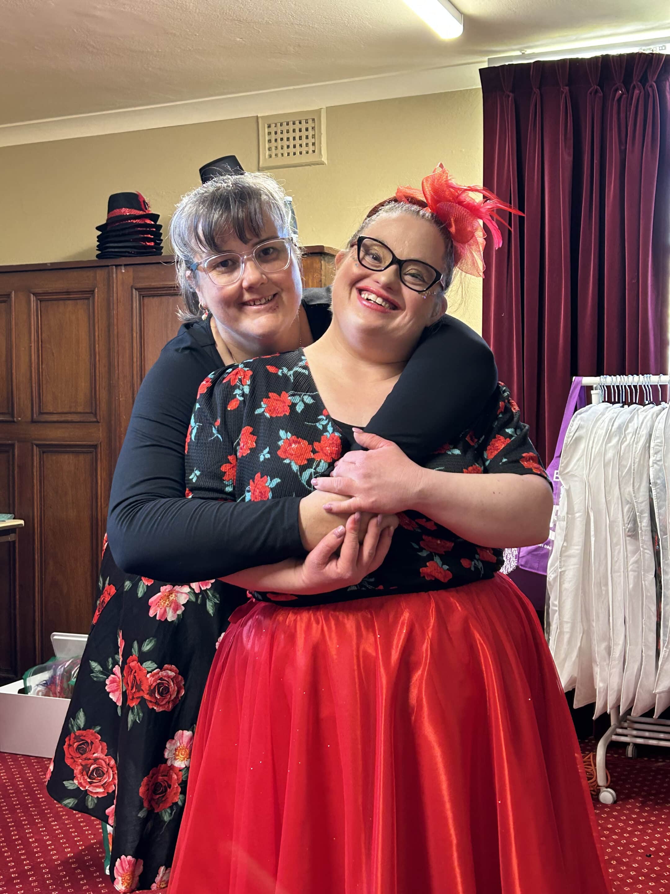 Woman with Down syndrome, wearing a dance costume, being hugged by her mother.
