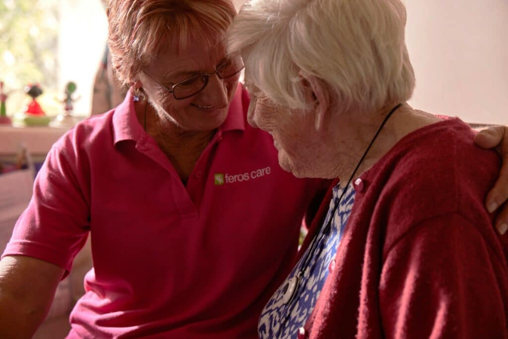Close up of Feros Care Community Support Worker Marion Fleming with her arm around Daisy.