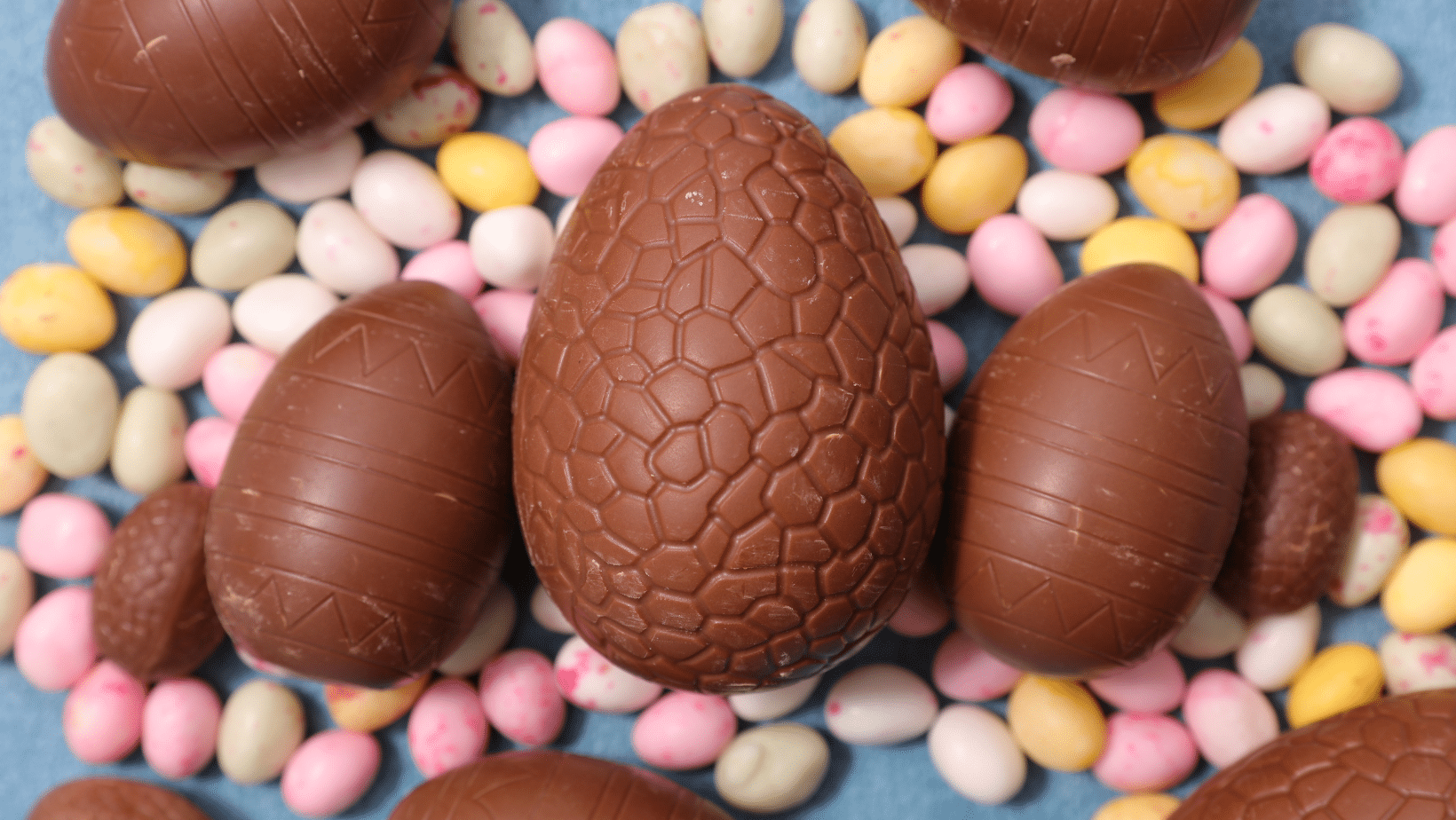 Three large chocolate Easter eggs surrounded by smaller Easter eggs