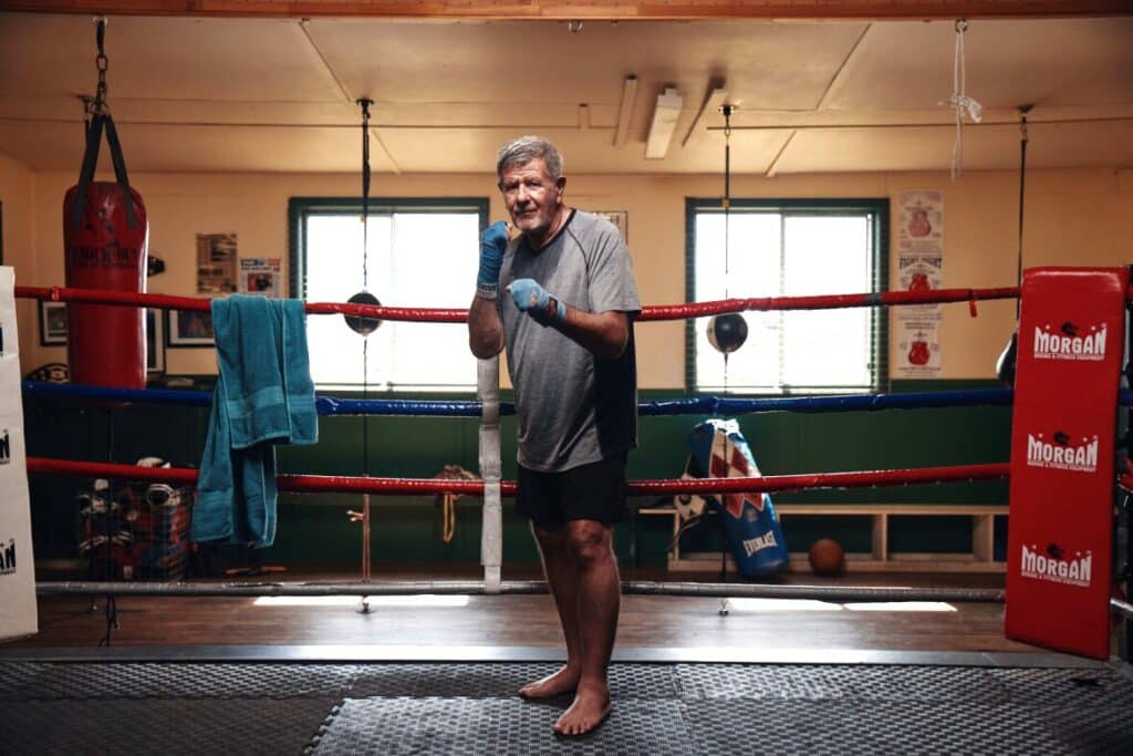 Feros Care client Darryl Ferney wearing boxing gloves standing in a boxing ring