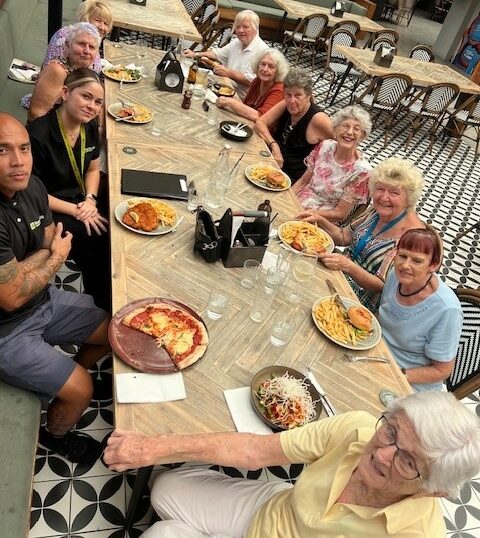 Feros Care clients on the Social Groups trip to Parkwood Village smiling and eating a delicious lunch