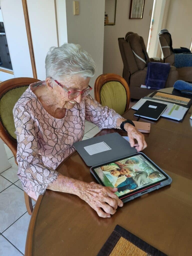 Feros Care client Yvonne using her iPad, smiling.