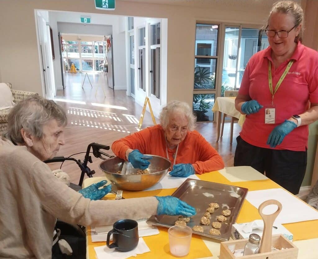 Bangalow Village residents sitting around a table together making Anzac biscuits.
