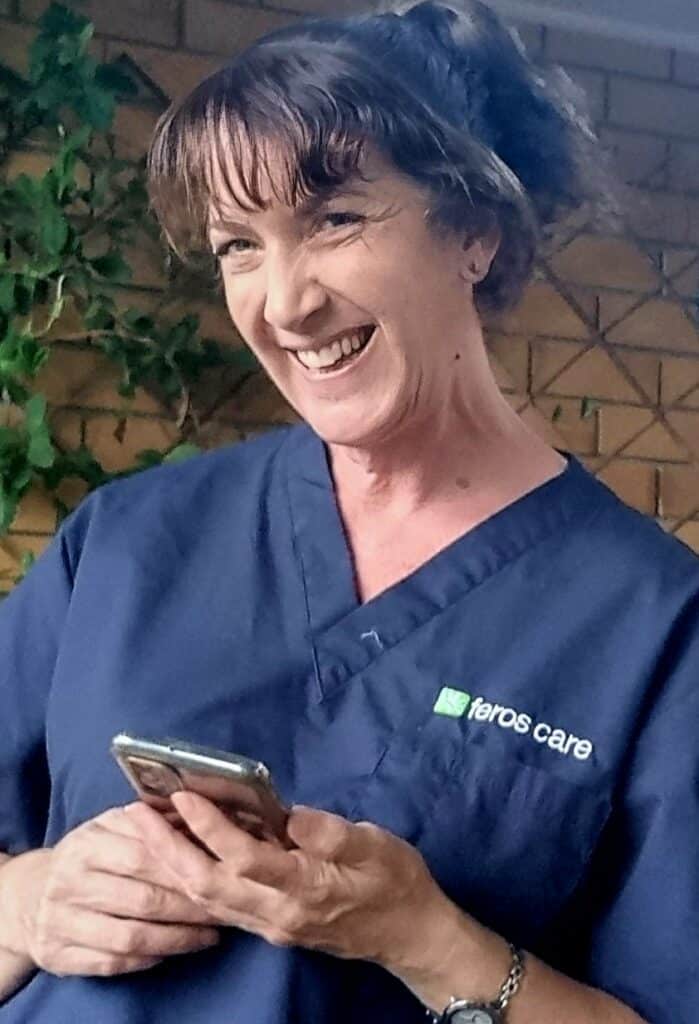 Feros Care Technical Support Officer Emmy smiling holding an iPhone