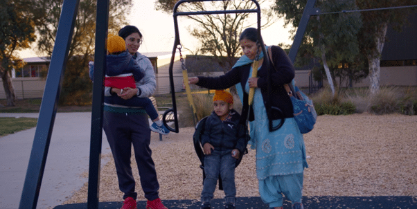 Indian mother with her month and two children playing on swings at park