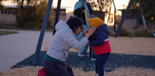 Mother in playground kissing child's nose