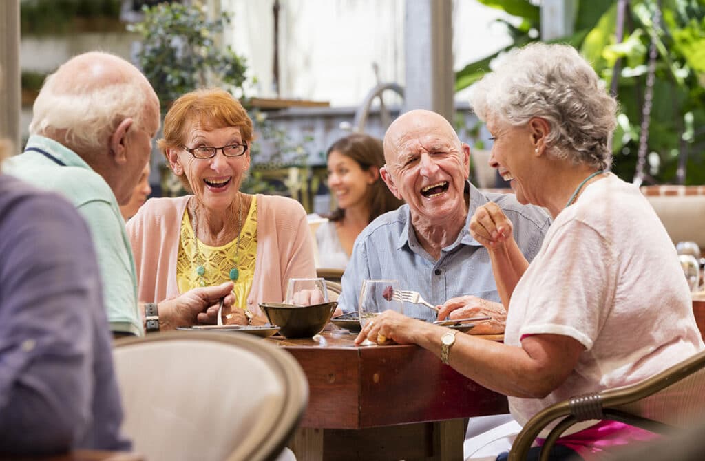 Photo of group of seniors laughing at lunch