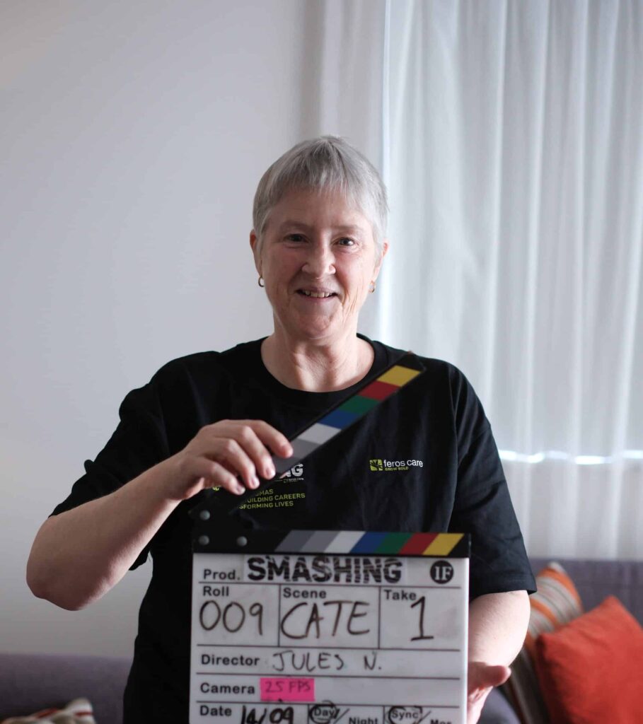 Cate Williams with clapper board for documentary series about SMASHING stereotypes in aged care employment