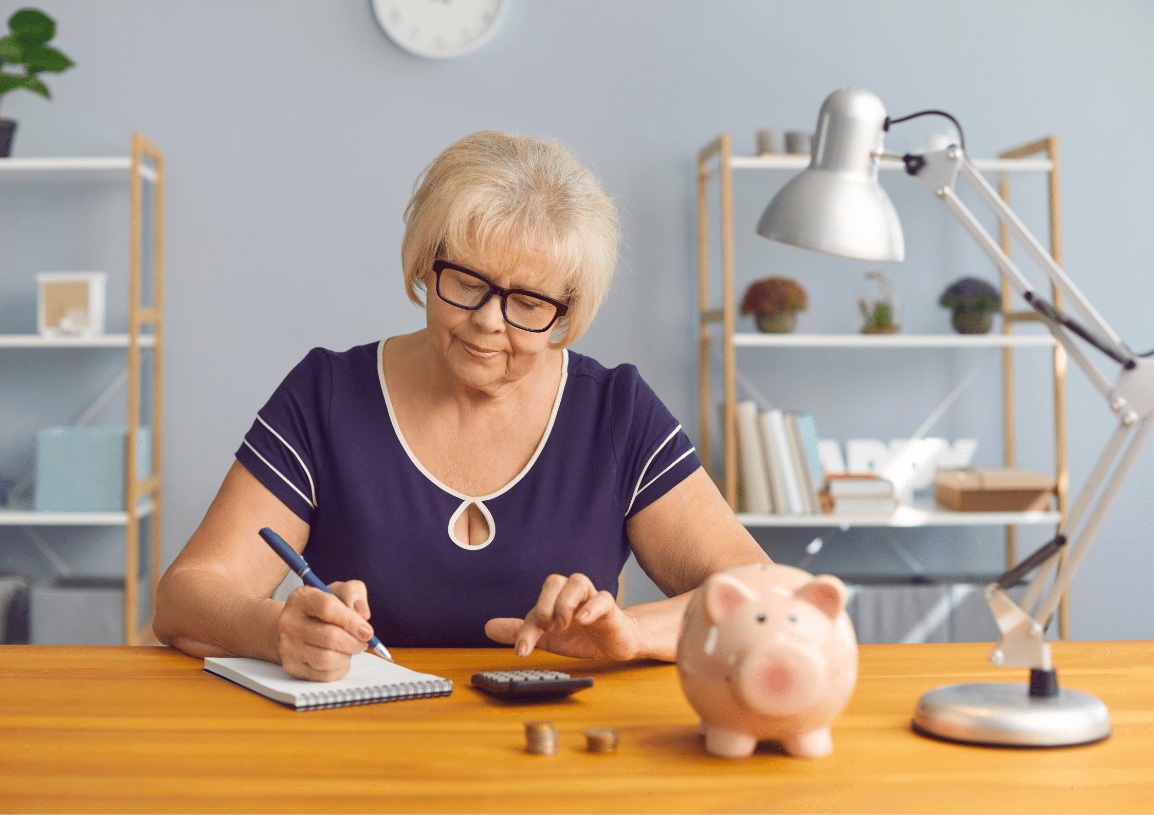 Female senior at tax time Photo of a female senior with a note pad, pen, calculator, piggy bank and some coins.