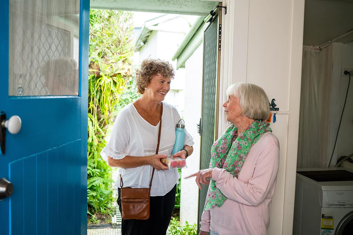 Photo of community visitor and client at entrance of home